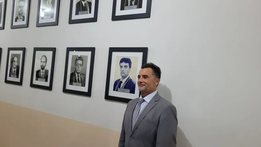 José Laurindo de Souza Netto posa ao lado da própria foto na galeria de juízes da Comarca de Arapongas  FOTO: TNONLINE