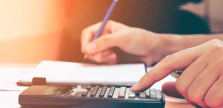 Close up young woman with calculator counting making notes at home, hand is writes in a notebook. Savings, finances, concept.