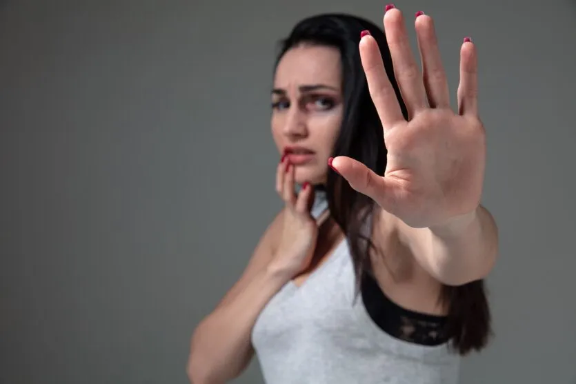Woman in fear of domestic abuse and violence, concept of female rights. Stop agression. Caucasian woman on grey looks upset, sad, depressed being victim of man or husband. Has bruises, hematomas.
