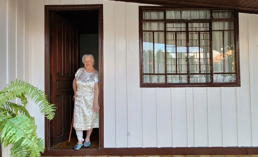 Dona Cleunice parada na porta da sua casa, onde mora desde 1983